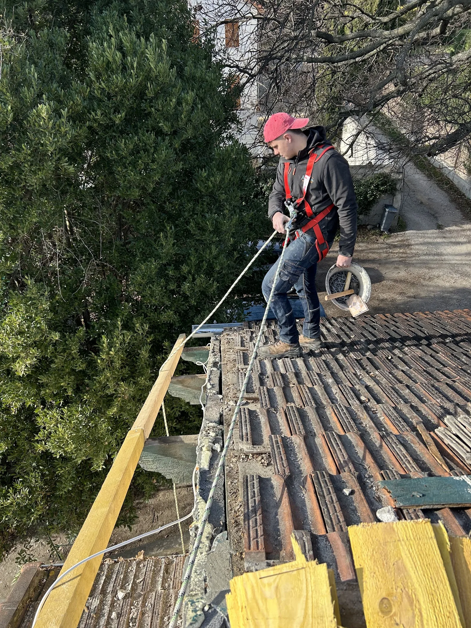 Kenny Brion, couvreur, harnaché et au travail sur une toiture à rénover